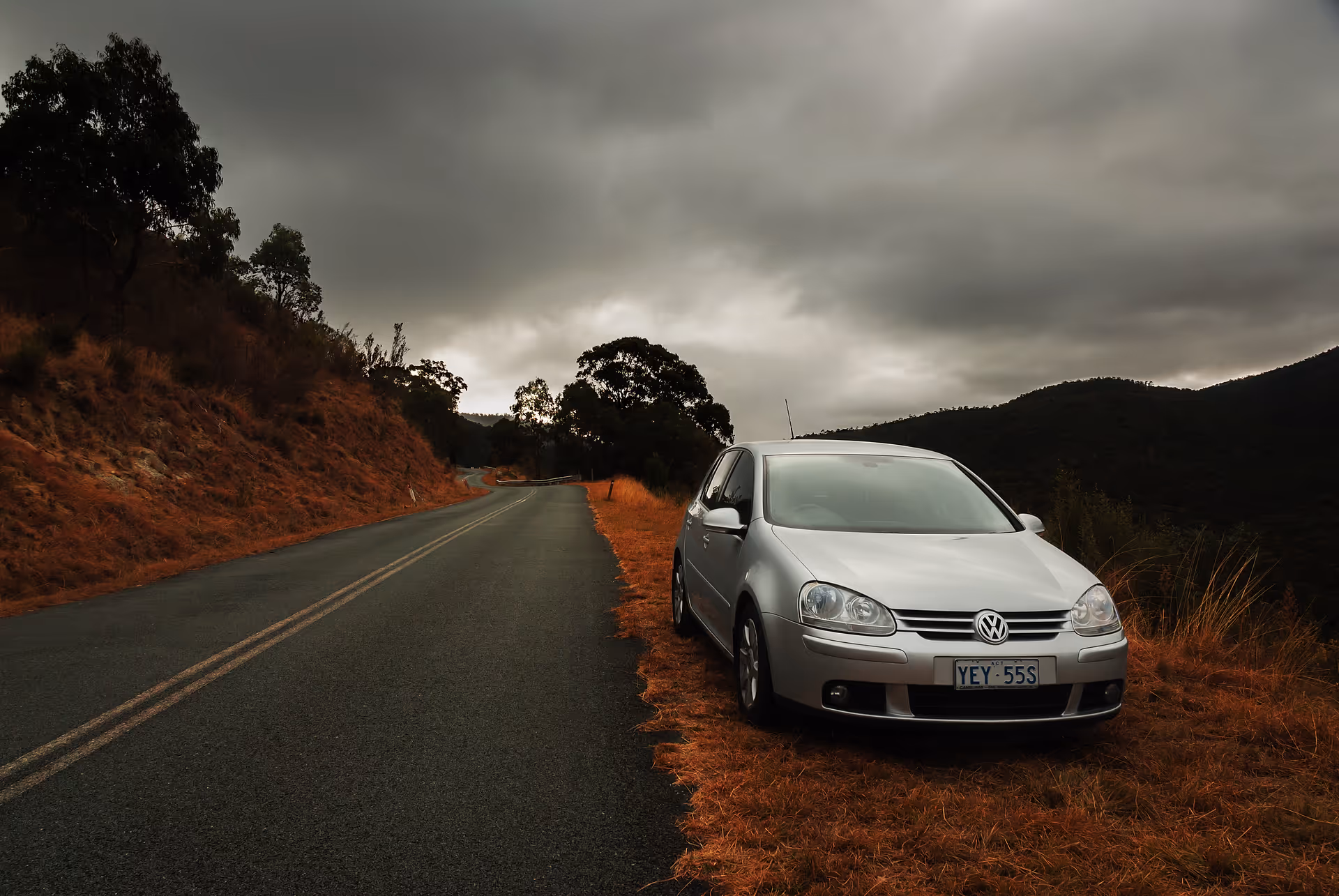 vw golf parked on the side of the road with a mountain in the background