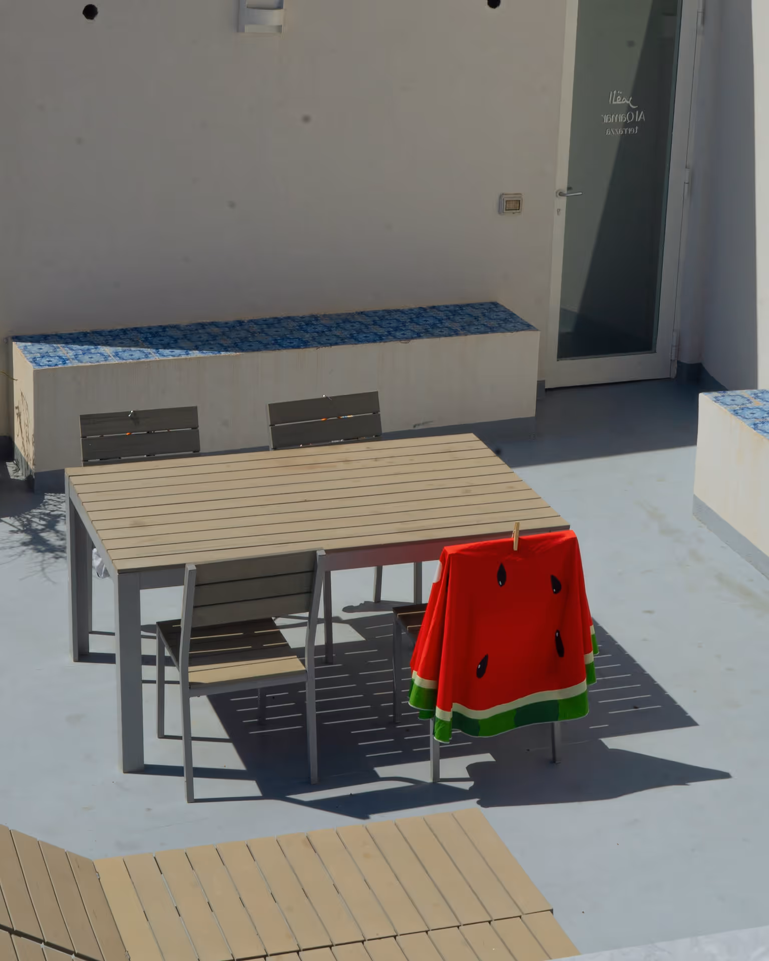 An outdoor dining set with a watermelon themed towel hanging on one of the chairs