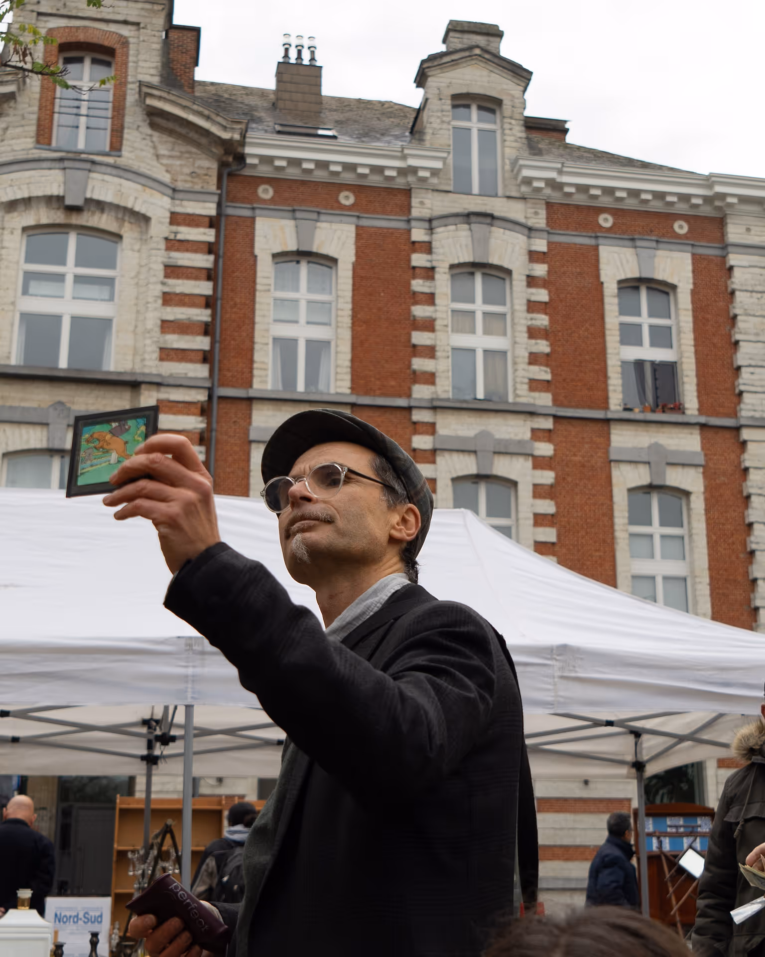 A man in a suit holds up an illustration of a man on a horse.